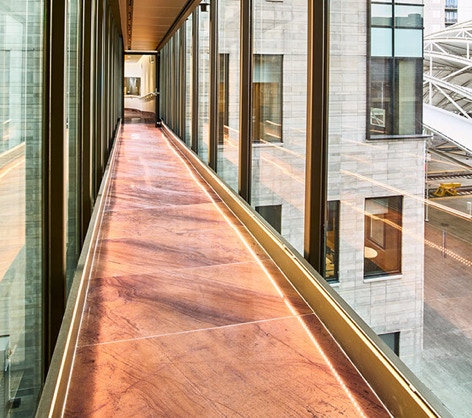 A hallway between two buildings with brown stone on the floor