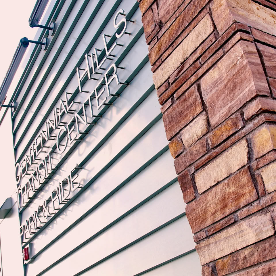 A building facade with horizontal metal siding and a stone column on the right side.