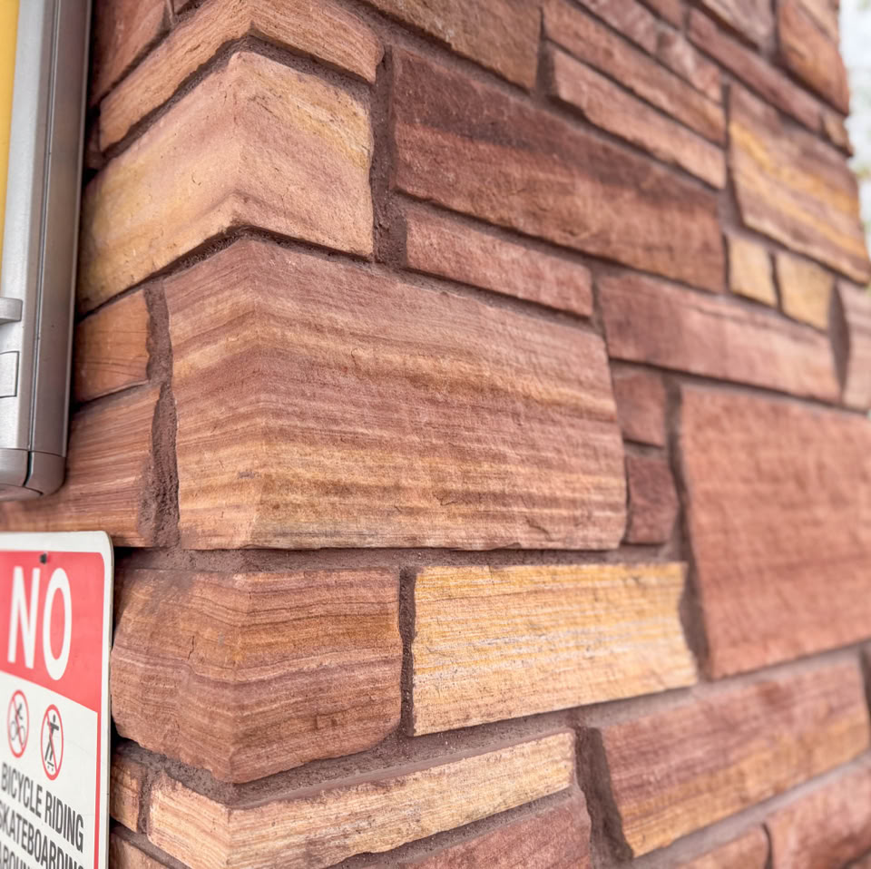 Brick wall corner with a "No" sign and a blurred background.