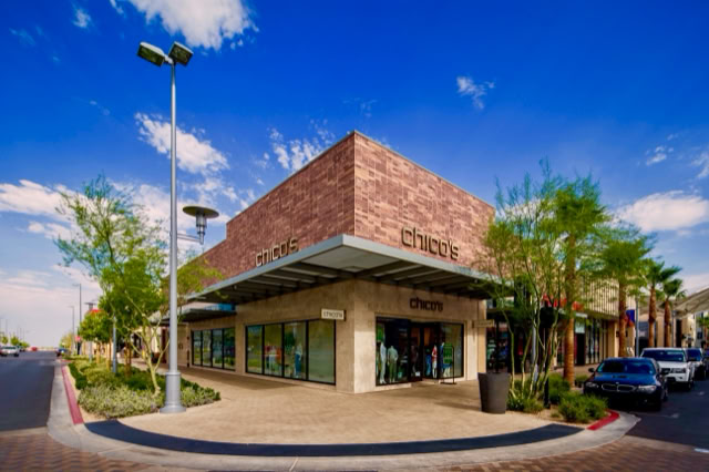 A modern Stone building with large glass windows, surrounded by trees and a streetlamp, under a clear blue sky. At downtown summerlin center in las vegas nv.