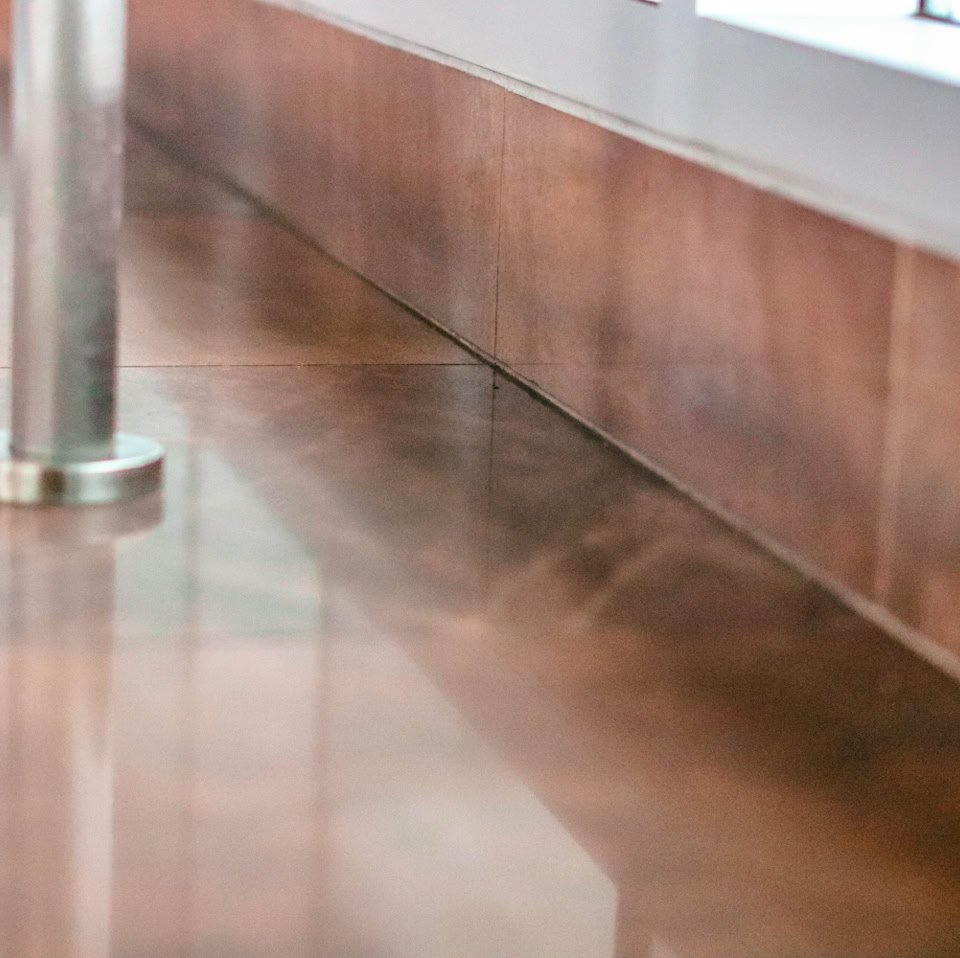 Polished brown floor with a metal pole and a wooden wall panel.