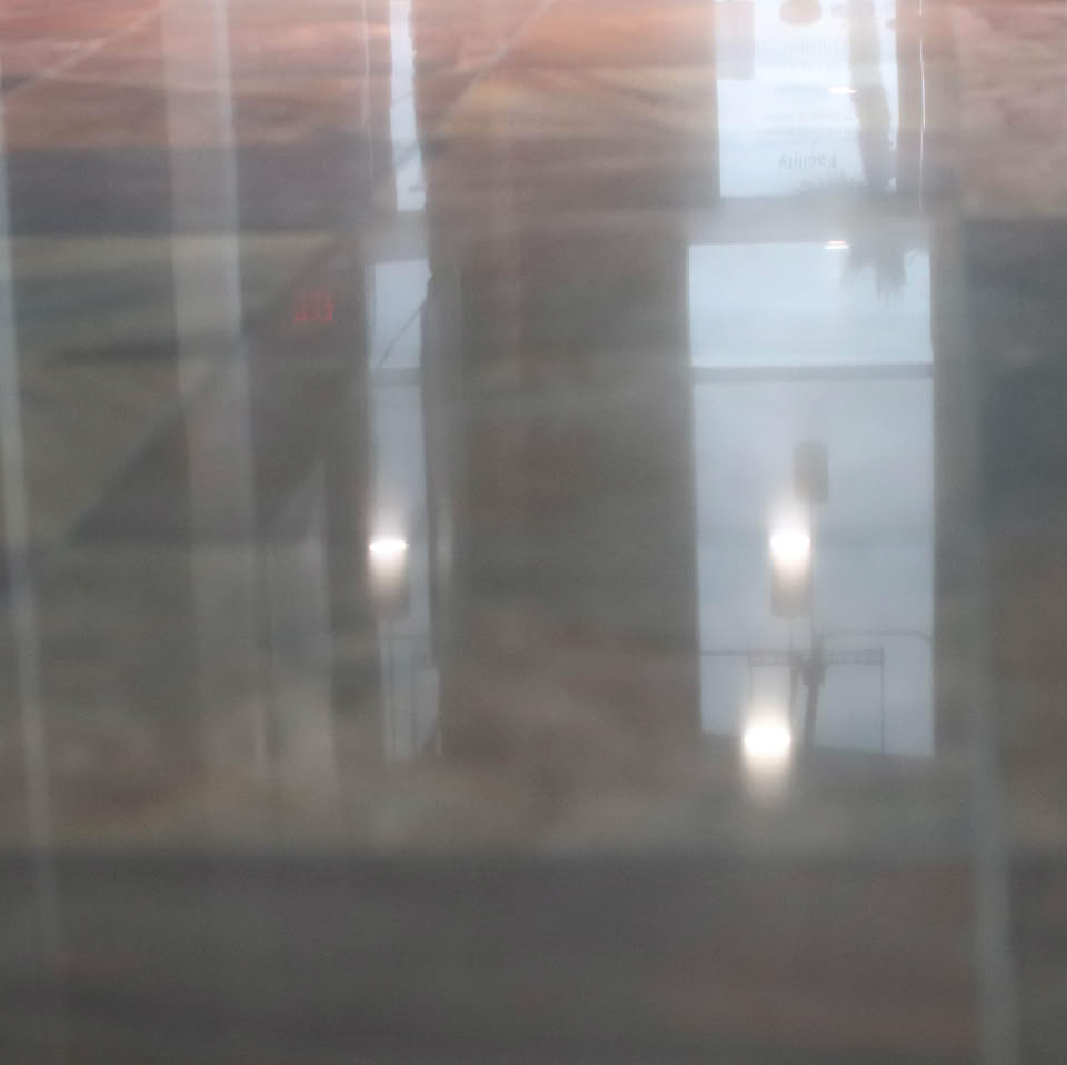 A polished floor with reflections of lights and windows.